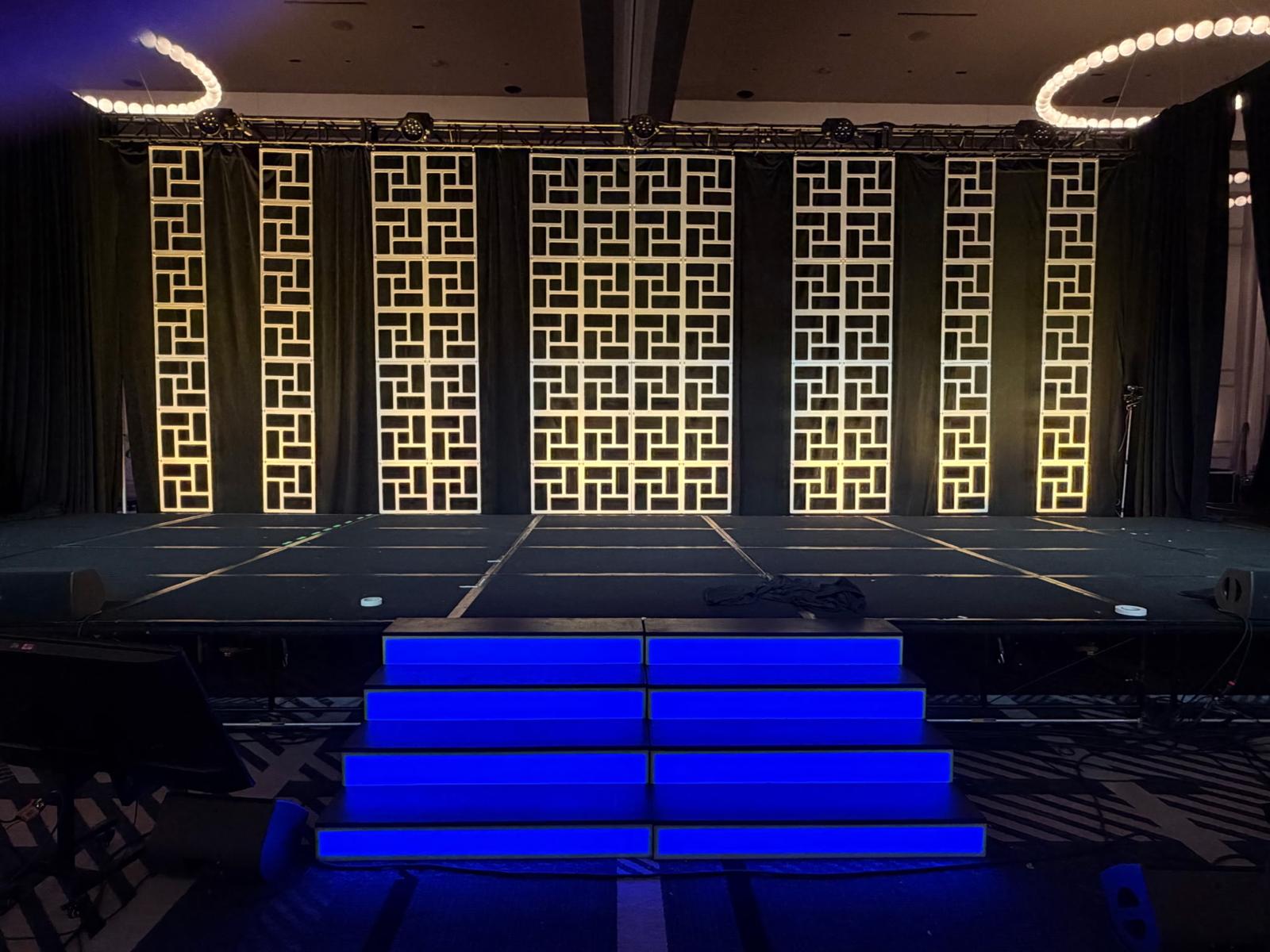 LED-lit neon blue scenic stairs with geometric lattice backdrop by MartinBuilt LLC